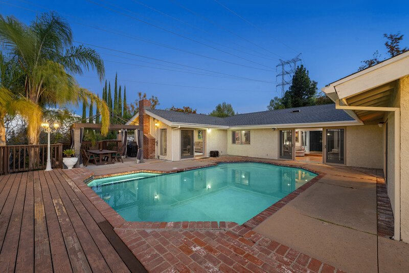 casa con alberca con acabados de madera y palmeras